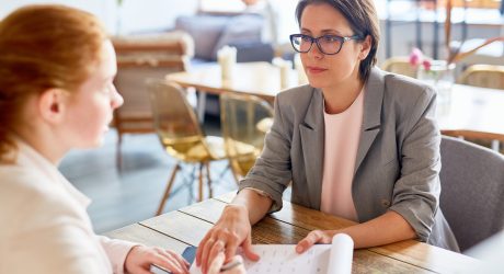 Business Partners Signing Contract Completion of successful negotiations: confident middle-aged entrepreneur passing contract for signature to her business partner while they sitting at cozy coffeehouse